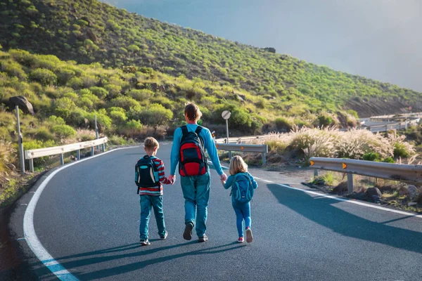 Far med två barn går på väg, resa i bergen — Stockfoto