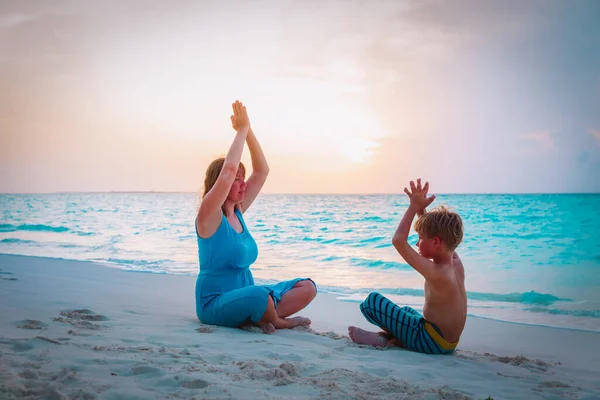 Silhueta de mãe e filho fazendo ioga na praia — Fotografia de Stock