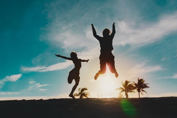 Feliz pai e filho pulando na praia do pôr do sol — Fotografia de Stock