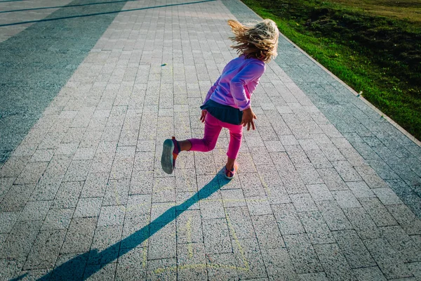 Menina jogando hopscotch no playground, crianças depois de jogos escolares — Fotografia de Stock