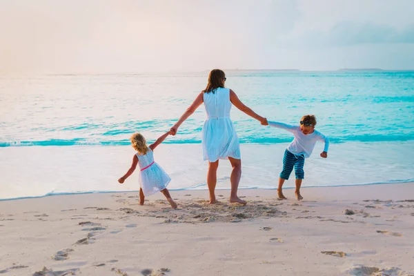 Mère avec petit fils et fille jouent sur la plage du coucher du soleil — Photo