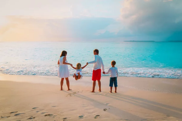 Çocuklu mutlu bir aile gün batımı kumsalında oynuyor. — Stok fotoğraf