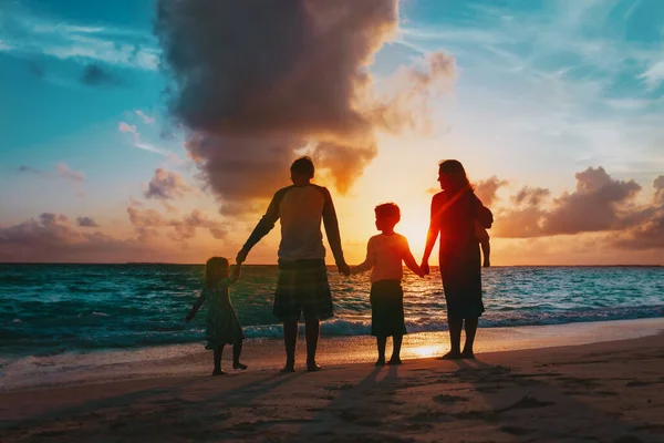 Familia feliz con los niños del árbol caminan en la playa del atardecer — Foto de Stock