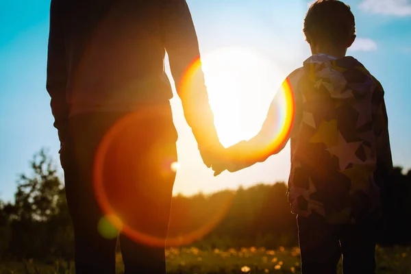 Silhueta de pai e filho de mãos dadas ao pôr do sol — Fotografia de Stock