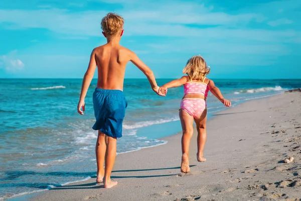 Mutlu kız ve erkek koşar sahilde dalgalarla oynarlar — Stok fotoğraf