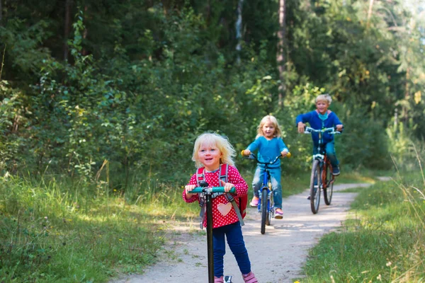 Crianças ativas felizes no passeio de bicicleta e scooter na natureza — Fotografia de Stock