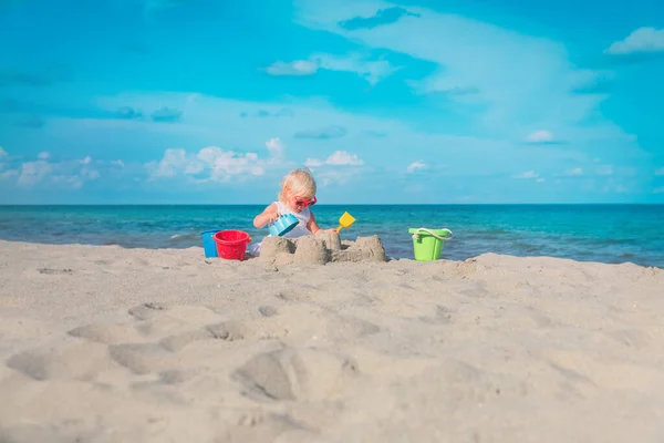 Niedliche kleine Mädchen spielen mit Sand am Strand — Stockfoto