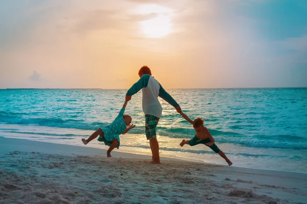 Glücklicher Vater mit Sohn und Tochter spielen am Strand bei Sonnenuntergang — Stockfoto