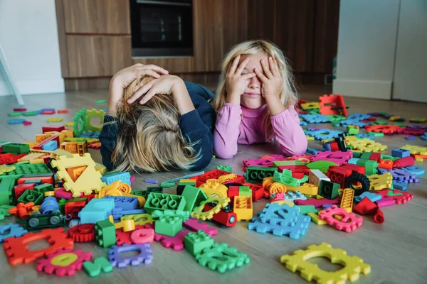 Menino e menina cansado estressado exausto com brinquedos espalhados dentro de casa — Fotografia de Stock