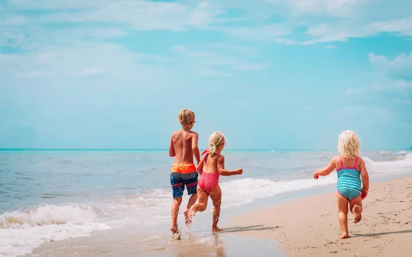 Happy kids - kleine jongen en meisjes-run spelen op het strand — Stockfoto