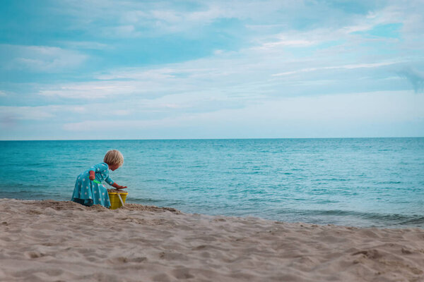 little girl play with sand on beach vacation