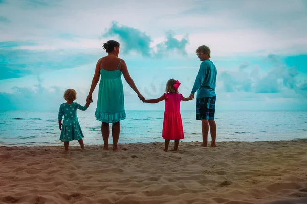 Rodina s dětmi při západu slunce na pláži — Stock fotografie
