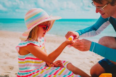 Güneş koruması - Babam sahilde küçük kız yüzüne güneş kremi sürmüş.