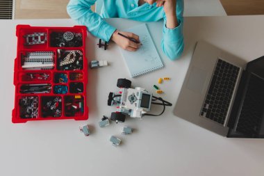 Plastik bloklardan robot yapan ve bilgisayarla programlayan çocuk.