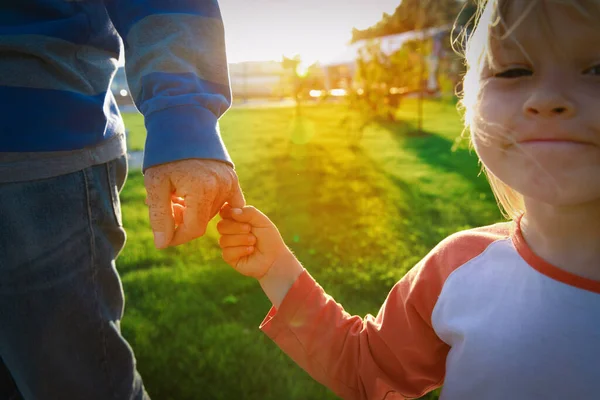 Ο πατέρας και η ευτυχισμένη κόρη κρατιούνται χέρι χέρι στο ηλιοβασίλεμα. — Φωτογραφία Αρχείου