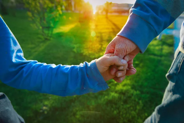 Pai e filho de mãos dadas ao pôr do sol, conceito de família — Fotografia de Stock