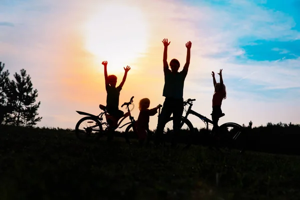 Família feliz em bicicletas e scooter ao pôr do sol natureza, pai e crianças exercem na natureza — Fotografia de Stock