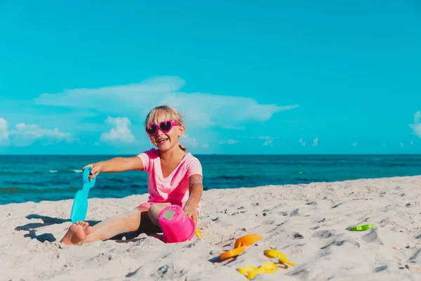 Мила маленька дівчинка грає з піском на пляжі — стокове фото