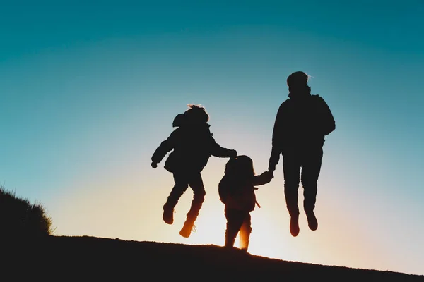 Силуэт счастливой семьи наслаждается путешествием на закате — стоковое фото