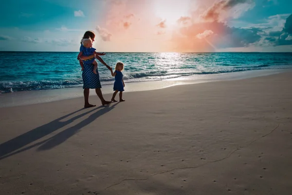 Moeder met kinderen lopen op zonsondergang strand — Stockfoto