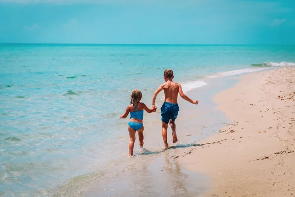 Šťastný chlapec a dívka běží na pláži — Stock fotografie