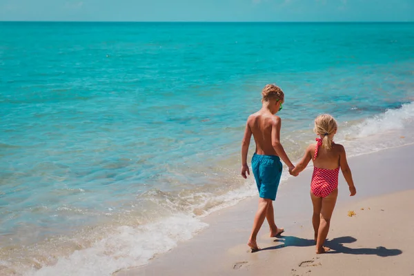 Jongen en meisje lopen op het strand, kinderen gaan zwemmen op zee — Stockfoto