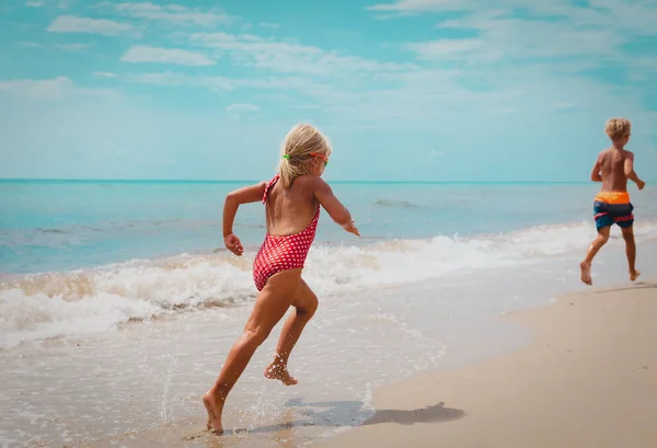 Heureux garçon et fille courir sur la plage — Photo