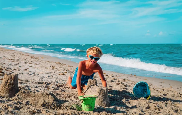 happy boy play with sand, kid building castle on beach