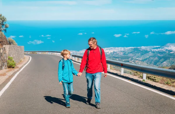 Father and son walking on road, family travel in mountains — Stock Photo, Image