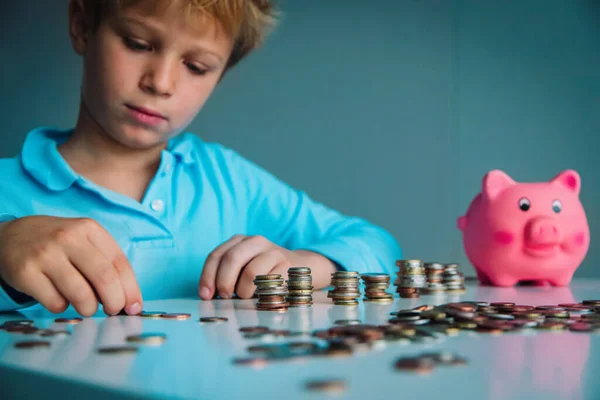Дитина заощаджує гроші, хлопчик кладе монети в скарбничку — стокове фото