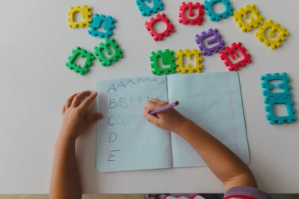 Liten flicka lära sig att skriva brev, hem lärande — Stockfoto