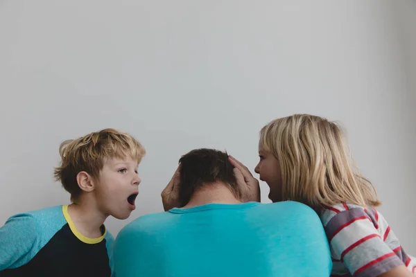 Gyerekek kiabálnak és zajt csapnak, míg apa feszült és fáradt. — Stock Fotó