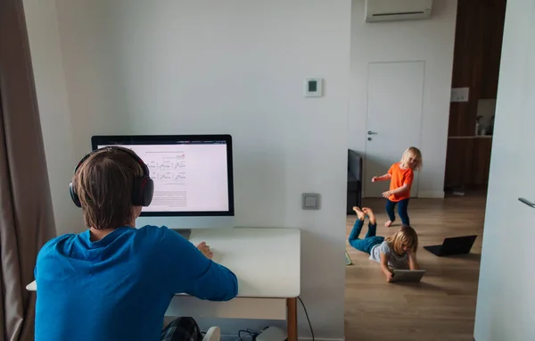 Familia quedarse en casa, el padre trabaja en la computadora mientras los niños bailan y miran la almohadilla táctil —  Fotos de Stock