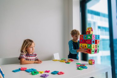 Çocuklar evde bulmaca oynuyorlar, kardeşler rekabet ediyor, aile içeride.