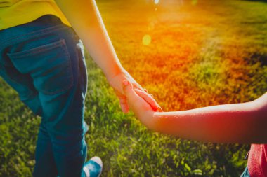 Erkek ve kız gün batımında el ele tutuşuyorlar.