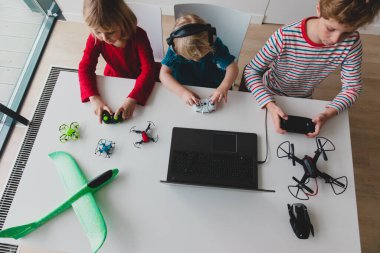 Çocuklar uçak ve İHA programlıyor, kız ve erkek çocuklar uzaktan kumandalı ve dizüstü bilgisayarlı.