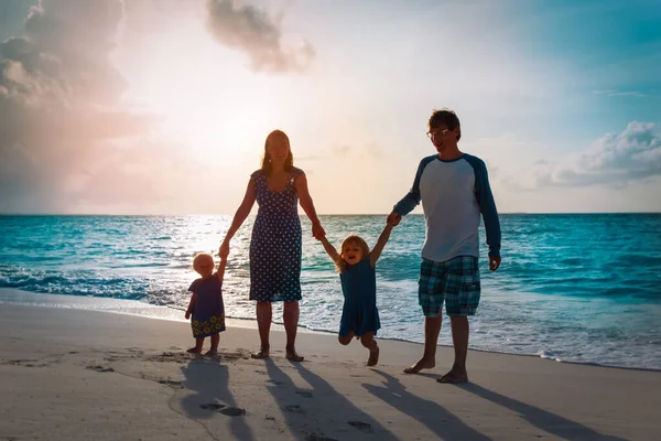 Gelukkig gezin met twee kinderen lopen op zonsondergang strand — Stockfoto