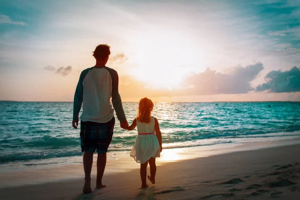 Vader en dochtertje wandelen op het strand bij zonsondergang — Stockfoto