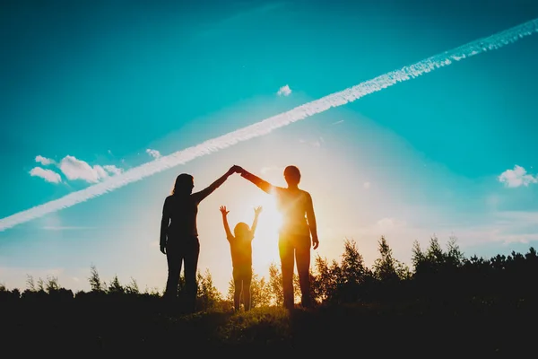 Семья с ребенком играют на закате природы, мама, папа и маленькая дочь веселятся вместе — стоковое фото