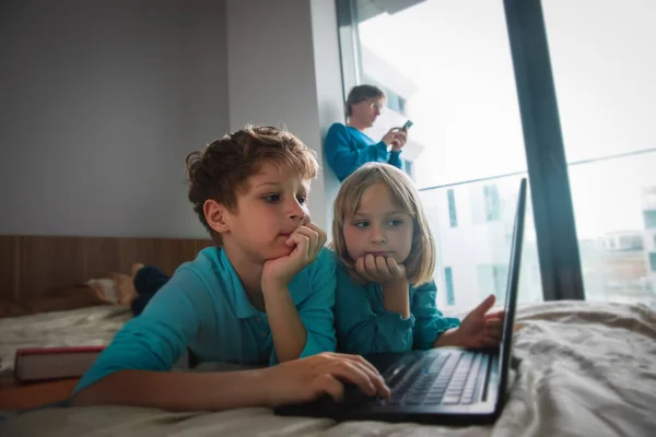 Familie bleibt zu Hause, Vater mit Handy und Kinder schauen drinnen auf Computer — Stockfoto