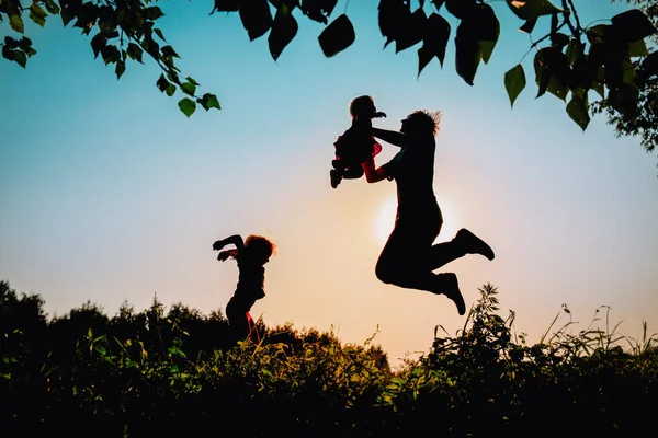 Siluety otce s dcerami hrají při západu slunce — Stock fotografie