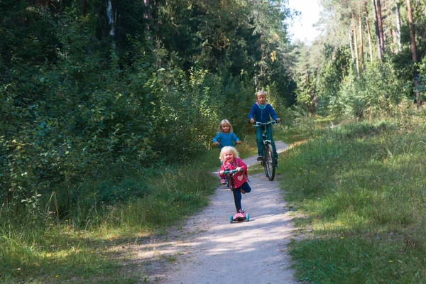 Niños activos felices en bicicleta y scooter paseo en la naturaleza — Foto de Stock