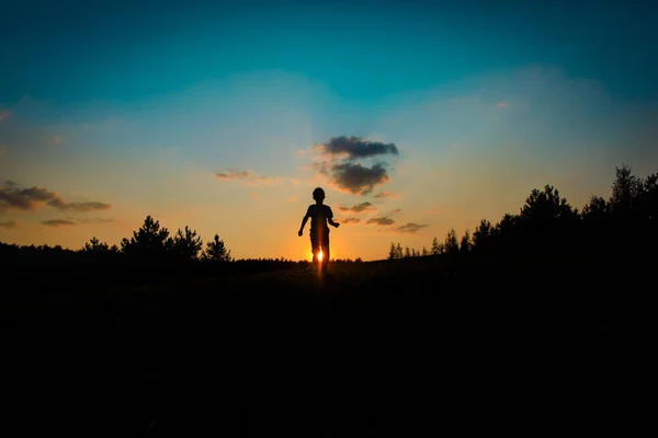 Silhuett av glad pojke springa och spela vid solnedgången — Stockfoto