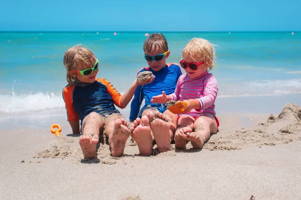 Dzieci bawią się piaskiem na plaży, chłopcy i dziewczęta cieszą się wakacjami na morzu — Zdjęcie stockowe