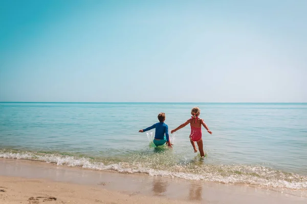 Счастливые мальчик и девочка бегут купаться на пляже — стоковое фото
