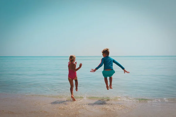 Šťastný chlapec a dívka běh plavat na pláži — Stock fotografie