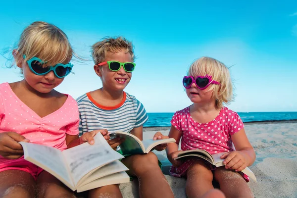 Mignon enfants heureux garçon et filles- lire des livres sur la plage, vacances en famille — Photo