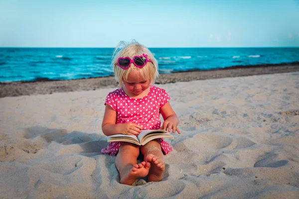 Mignonne petite fille lecture livre à la plage — Photo