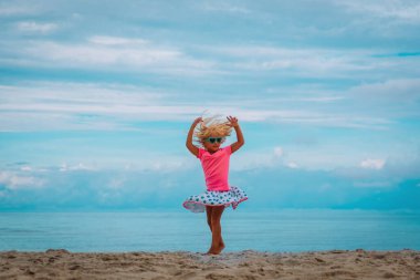 Tatlı küçük kız dansı, yaz kumsalında çocuk oyunu.