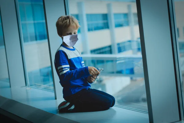 Dziecko z maską patrzące na samoloty na lotnisku, podróżujące podczas koronowirusa — Zdjęcie stockowe
